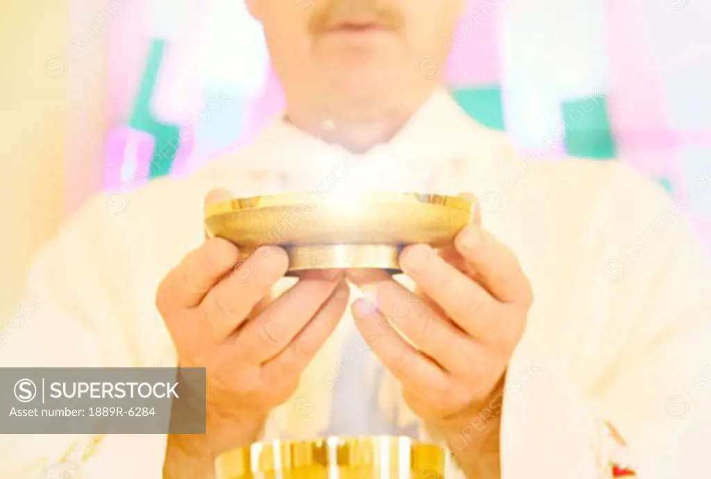 Priest holding bowl of wafers