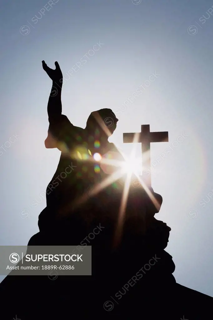 silhouette of a statue and cross with a sun burst, strasbourg, france