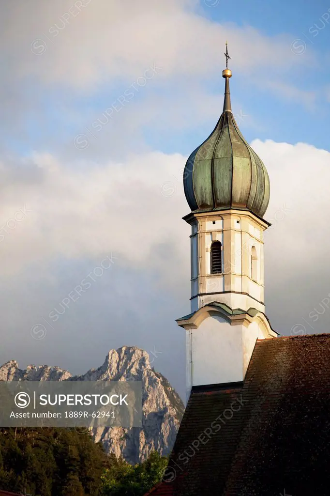 church bell tower with a mountain peak in the background, fussen, germany