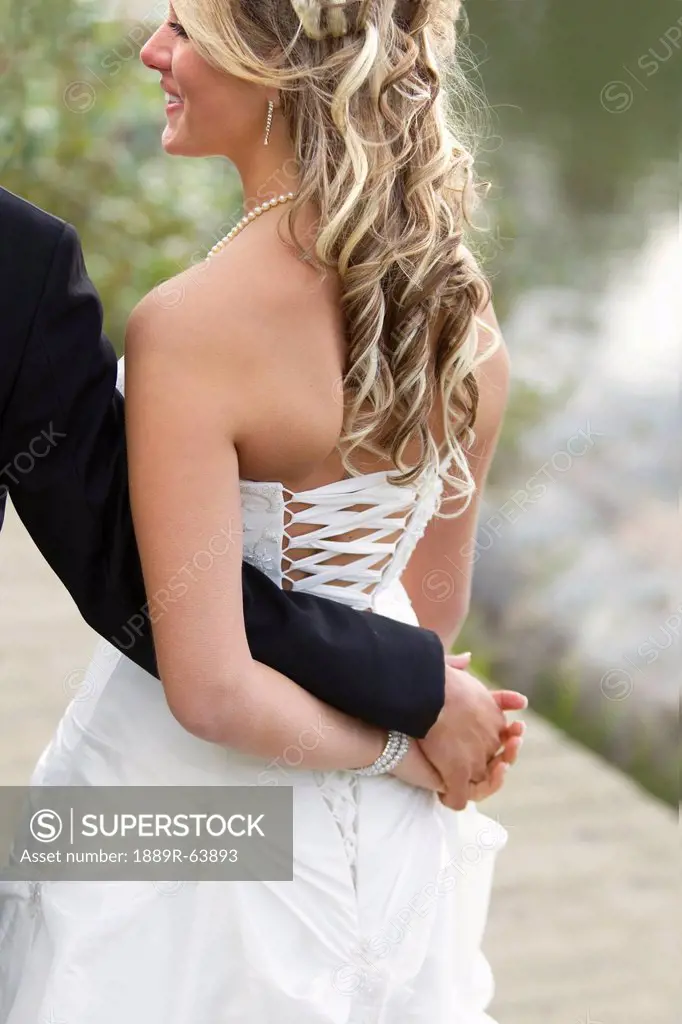 a bride holds her groom´s hand behind her back, edmonton, alberta, canada