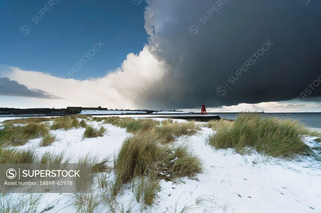 dark clouds and blue sky over a red lighthouse along the coast in the winter, south shields, tyne and wear, england