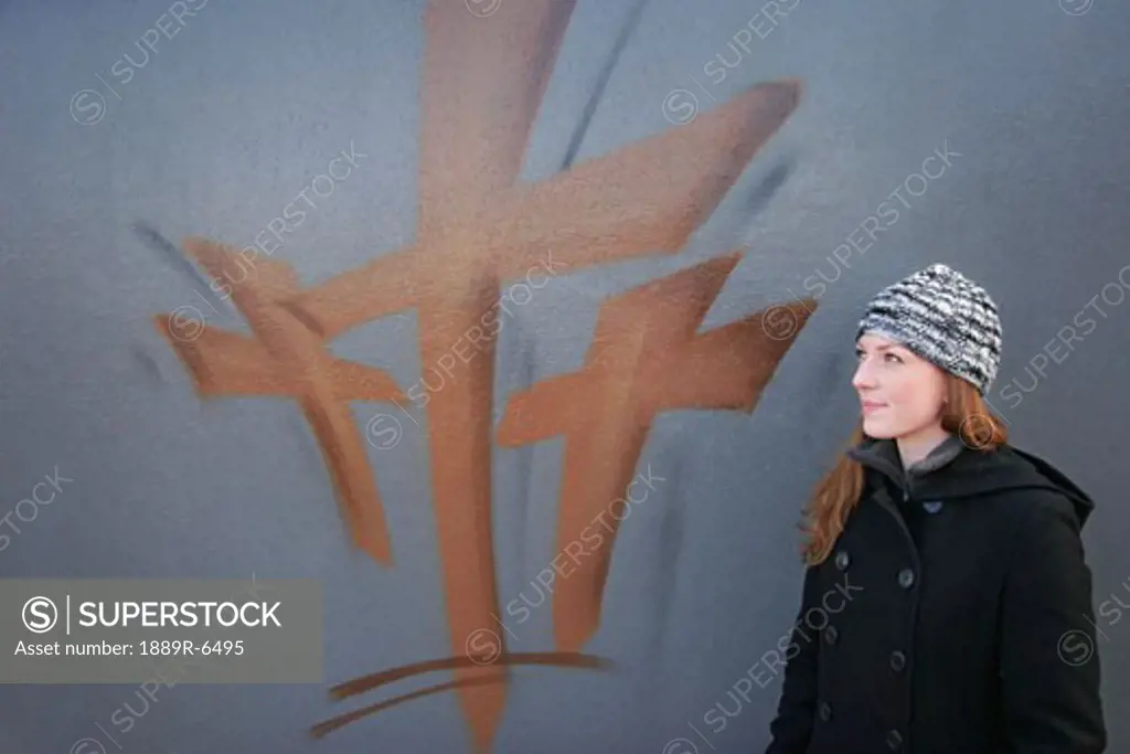 Woman stands by painting of the cross