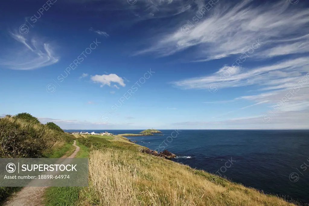 path along a cliff and a lighthouse in east cork in munster region, ballycotton, county cork, ireland