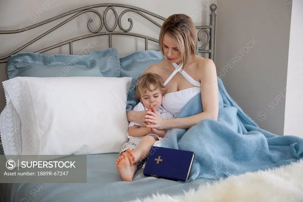toddler and mother in bed praying together, jordan, ontario, canada