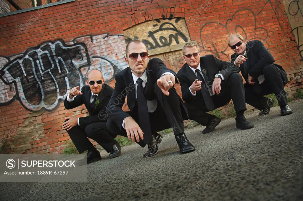 four groomsmen wearing sunglasses in front of a graffiti wall