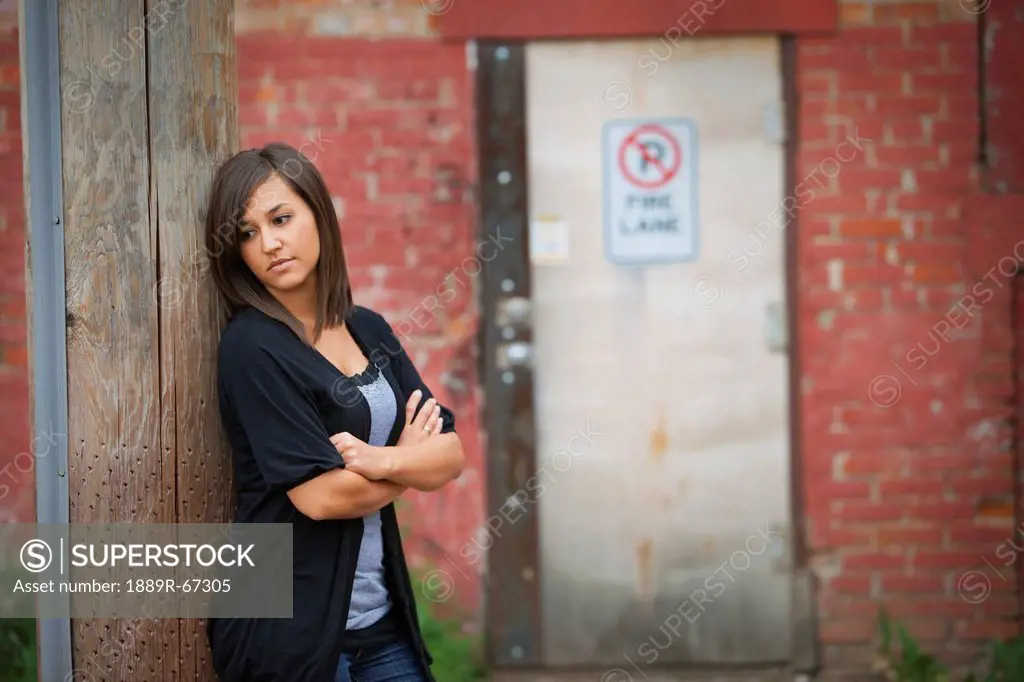 a young woman stands alone in an alley