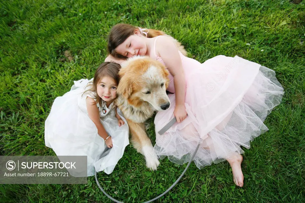 two sisters in dresses hug their rescue dog outdoors, duncan, vancouver island, british columbia, canada