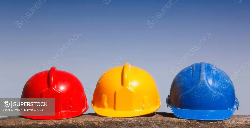 three hard hats in a row in primary colors red, yellow and blue