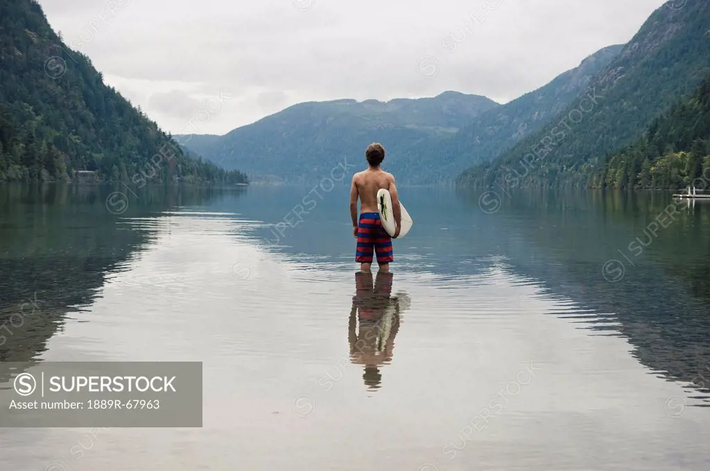 a young man wearing a swimsuit stands in cameron lake, british columbia canada
