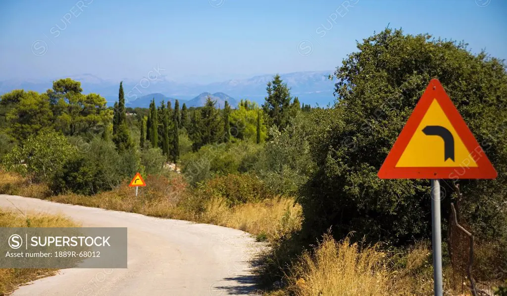 road signs along a curve in the road, ithaca greece