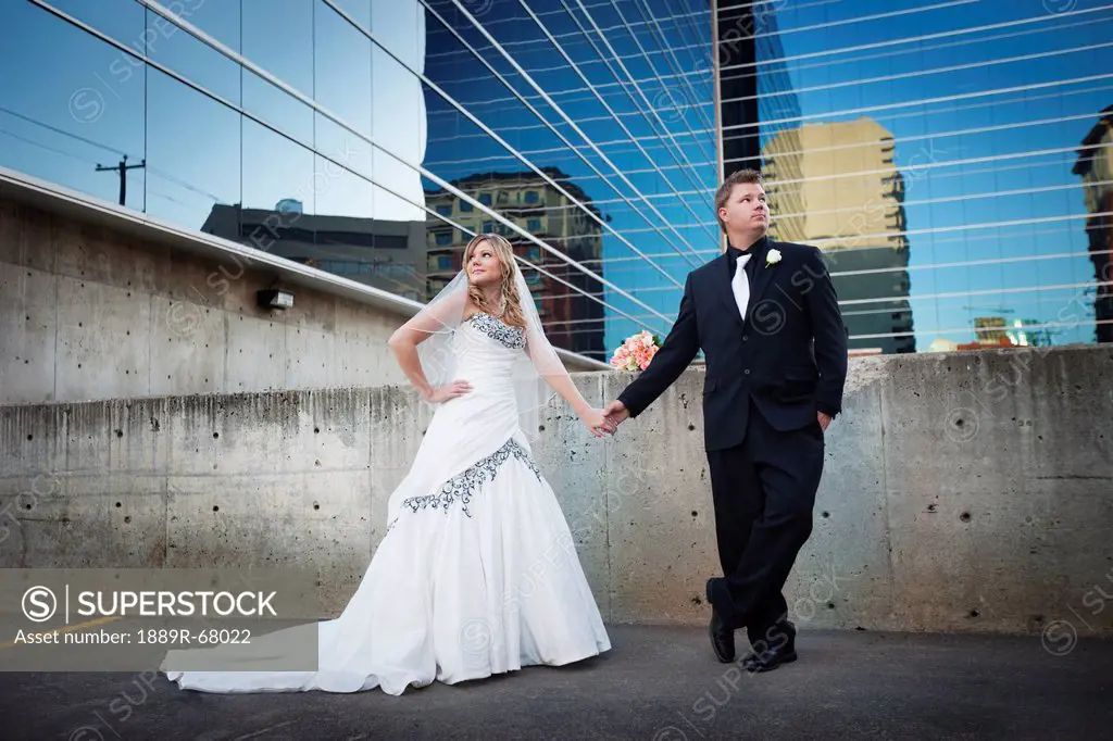 a bride and groom posing in front of a mirrored building, edmonton alberta canada
