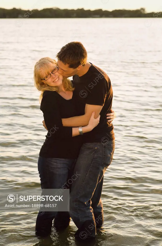 a young couple in an embrace while standing in the lake, willmar minnesota united states of america