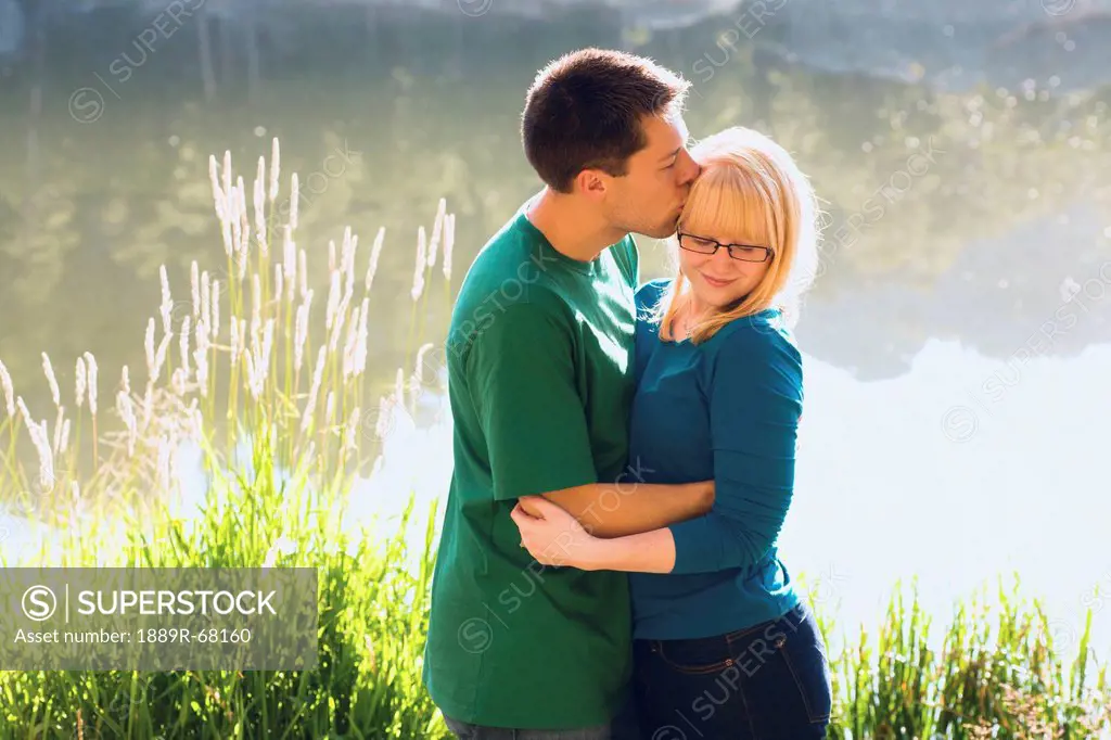 a young couple kiss in front of sylvan lake, south dakota united states of america