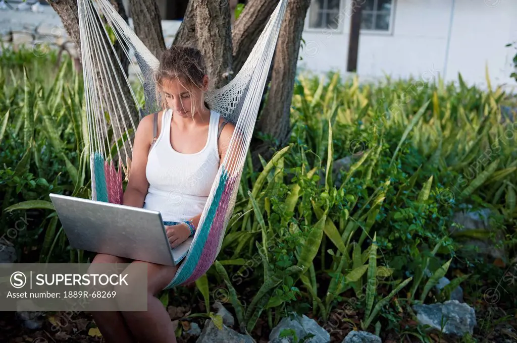 girl working on a laptop while sitting in a hammock, south caicos turks and caicos islands