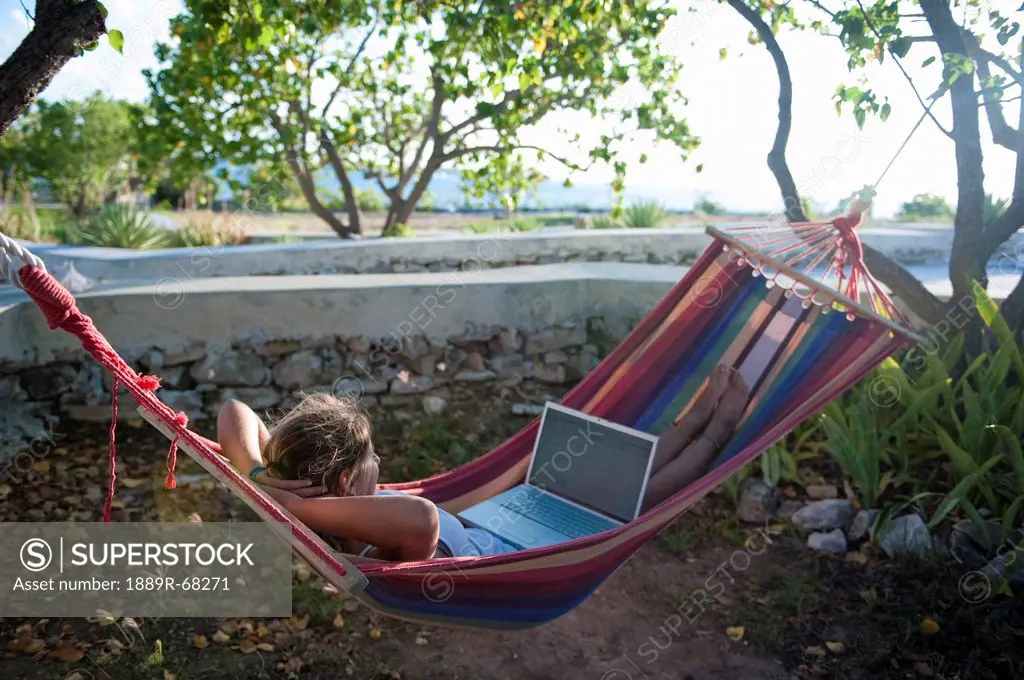 girl using a laptop while sitting in a hammock, south caicos turks and caicos islands
