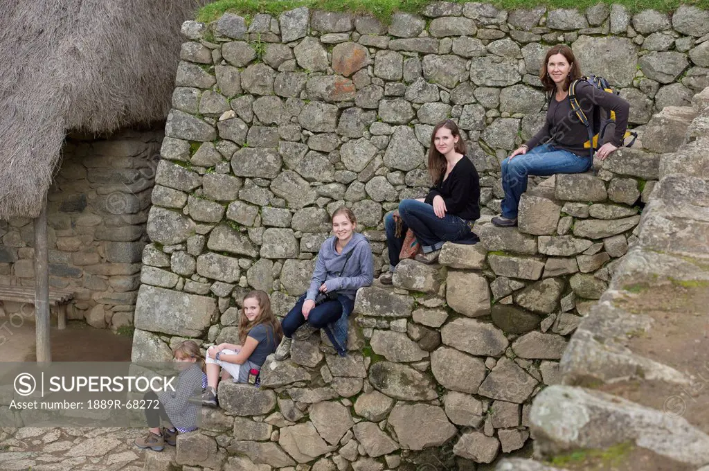 five girls posed sitting on steps in machu picchu, peru