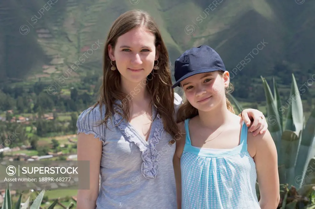 two sisters standing together with sacred valley below them, sacred valley peru