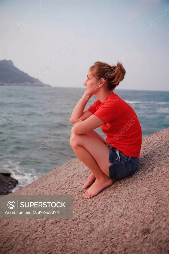 a woman sits on a rock gazing out at the ocean, koh tao thailand