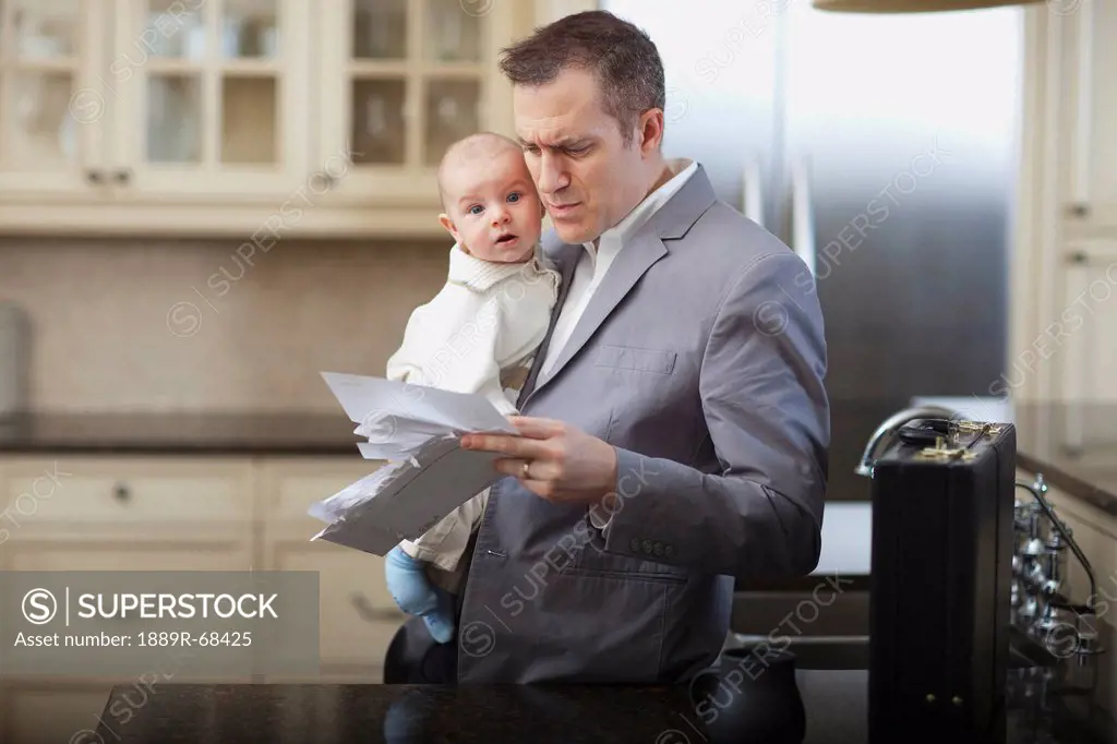 businessman father with baby stressing over household bills, jordan ontario canada