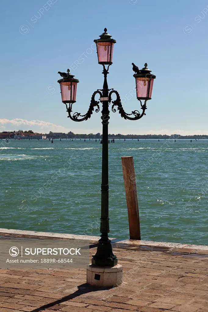 a lampstand on the promenade along the water, venice italy