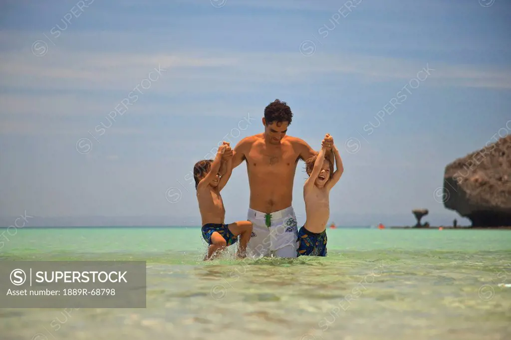 a man plays in the water with two boys at los islotes national marine park espiritu santos island, la paz baja california mexico