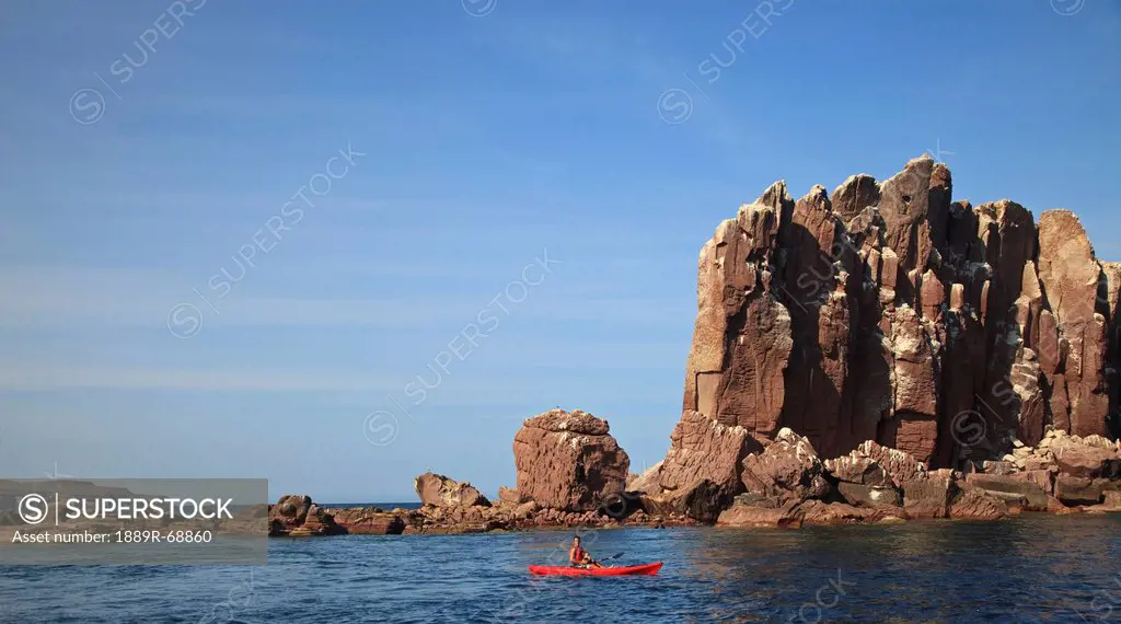 a father and son paddle in a red boat at los islotes national marine park espiritu santo island, la paz baja california mexico