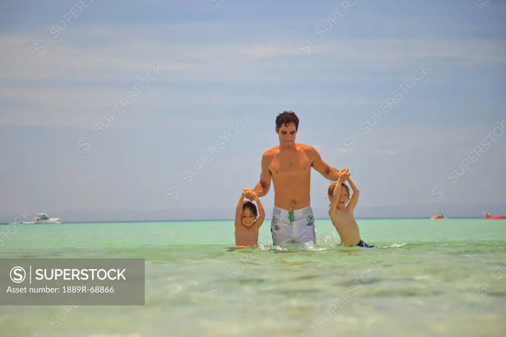 a father plays with his sons in the ocean at los islotes national marine park espiritu santo island, la paz baja california mexico