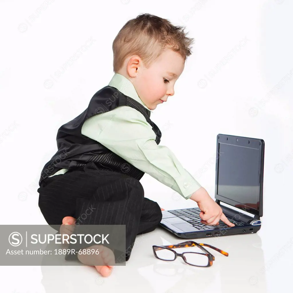 a young boy dressed in a suit using a laptop computer, edmonton alberta canada
