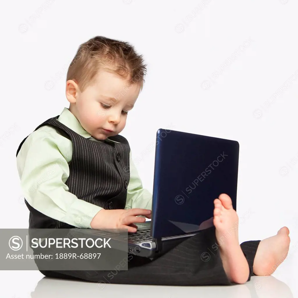 a young boy dressed in a suit using a laptop computer, edmonton alberta canada