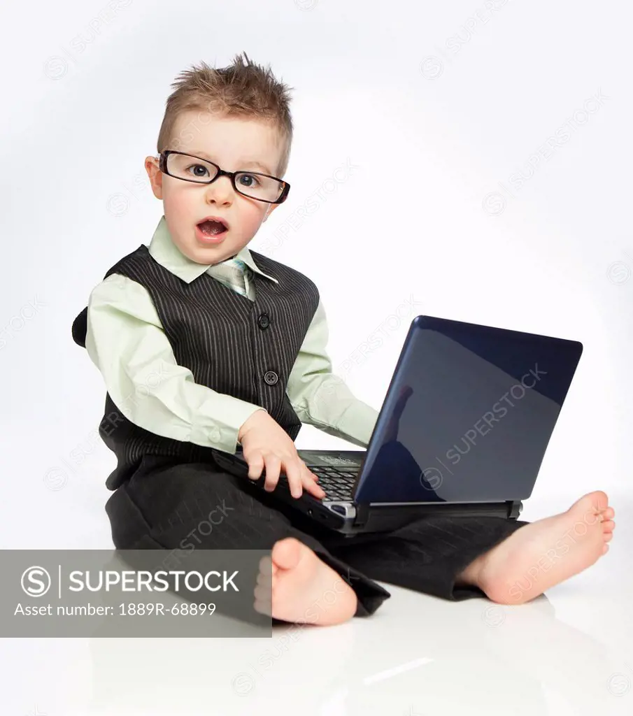 a young boy wearing a suit and eyeglasses using a laptop computer, edmonton alberta canada