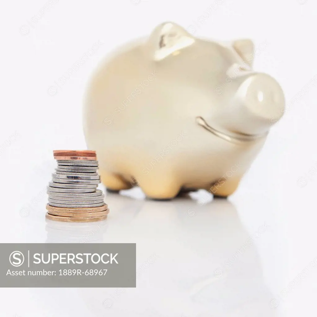 a stack of coins beside a piggy bank