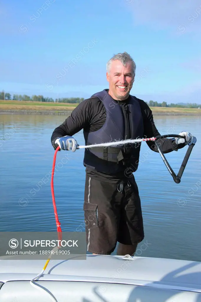 a man holding a water skiing rope in his hands at the back of a boat, troutdale oregon united states of america