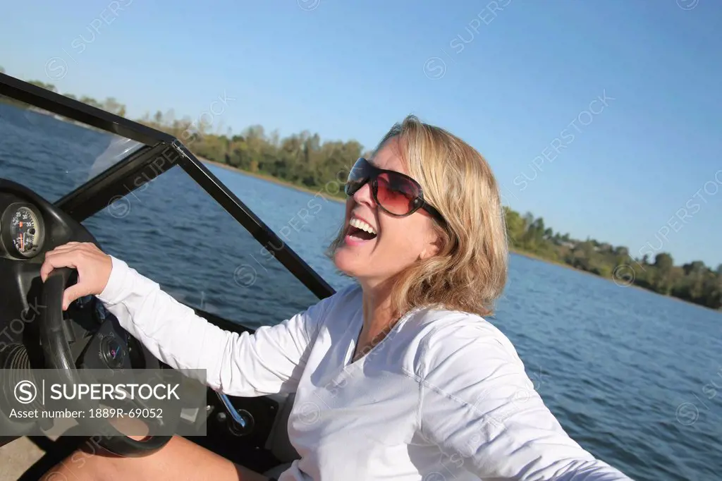 a woman driving a ski boat and laughing, portland oregon united states of america