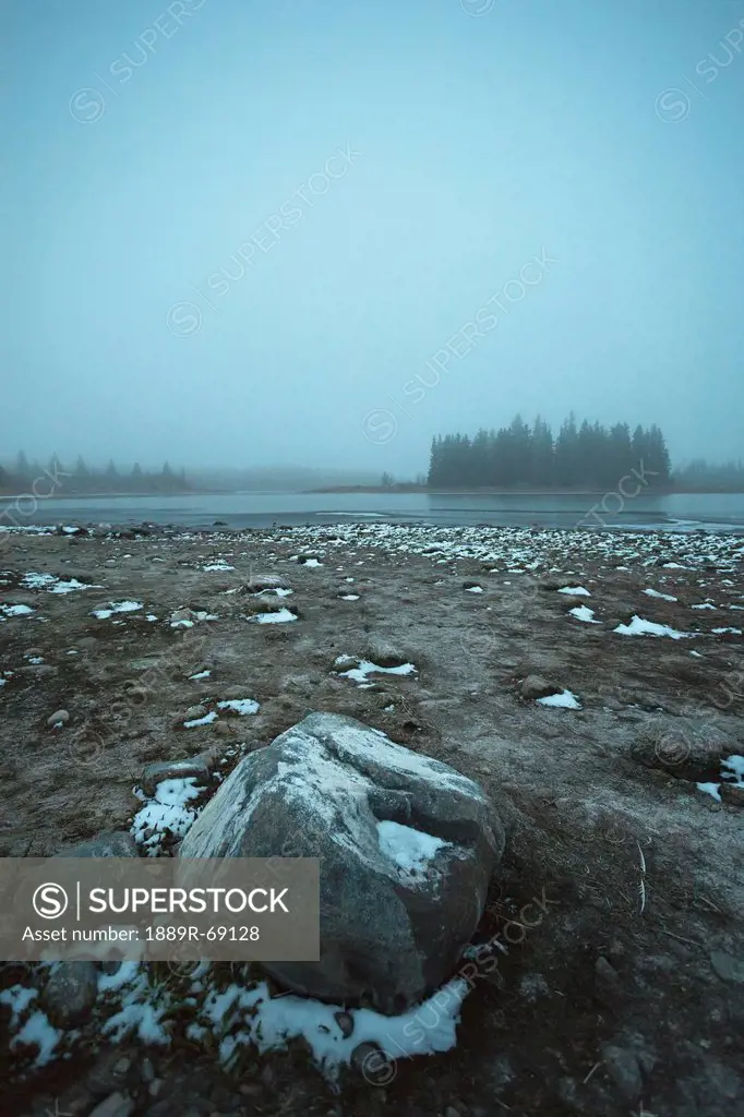 snow on the shore of astotin lake on a foggy evening, edmonton alberta canada