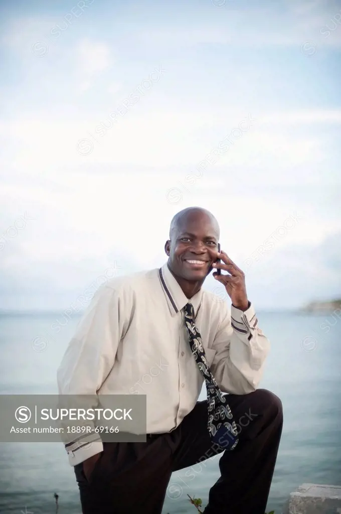 businessman using a cell phone at the water´s edge, south caicos turks and caicos islands