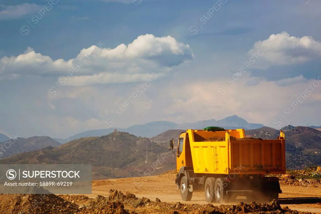 dump truck laden with earth driving on construction site, malaga province spain