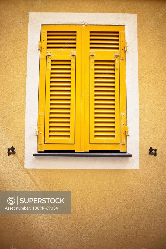bright yellow shutters on a pale yellow wall, italy