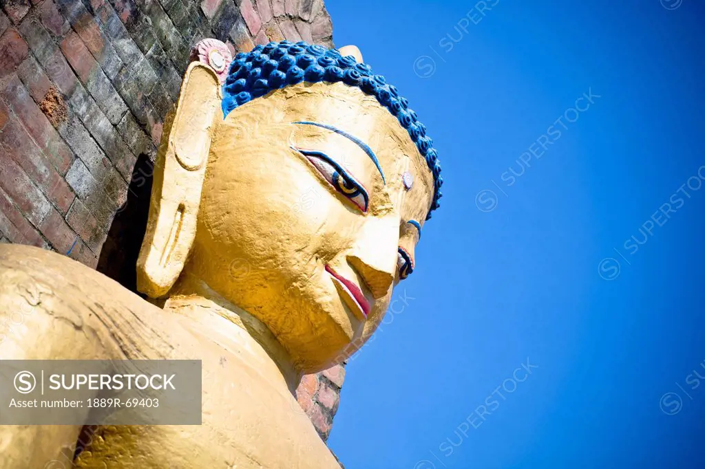 a buddhist statue of female likeness against a blue sky, kathmandu nepal