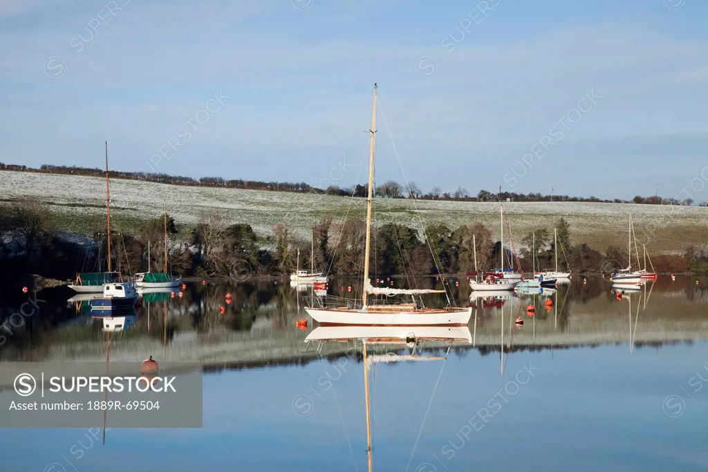 boats moored in the water along the shoreline in winter near carrigaline, county cork ireland