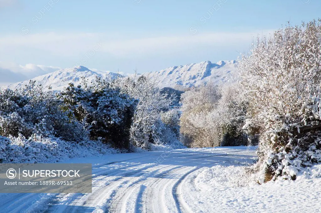 a snow covered road in winter, tahilla county kerry ireland