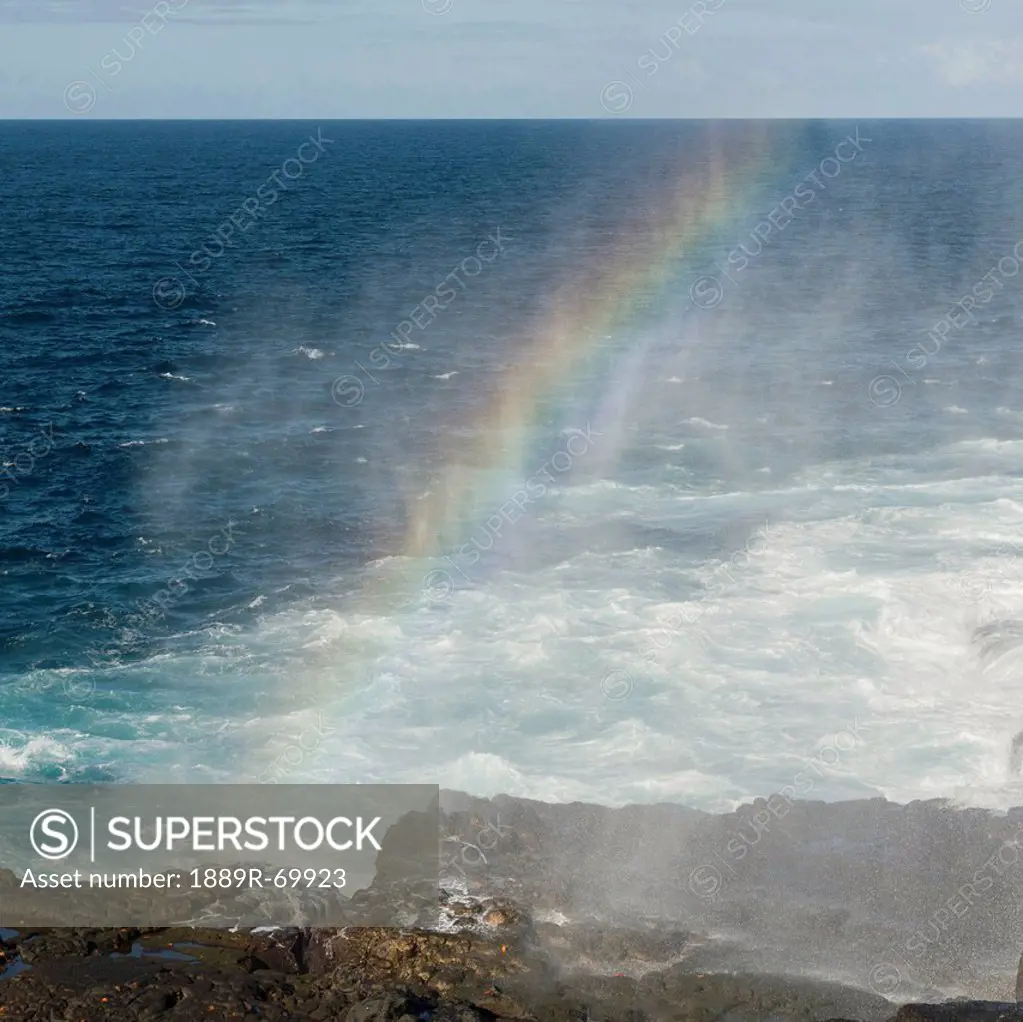 rainbow at a blow hole on the coast, galapagos, equador