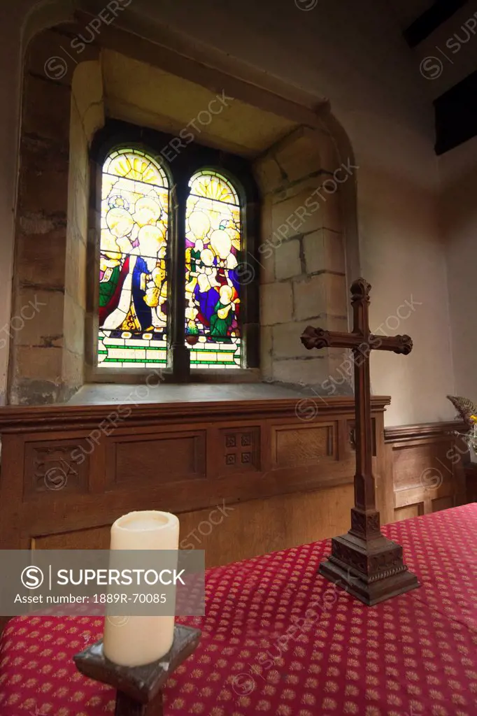 stained glass window and a table with a cross inside a church, northumberland england