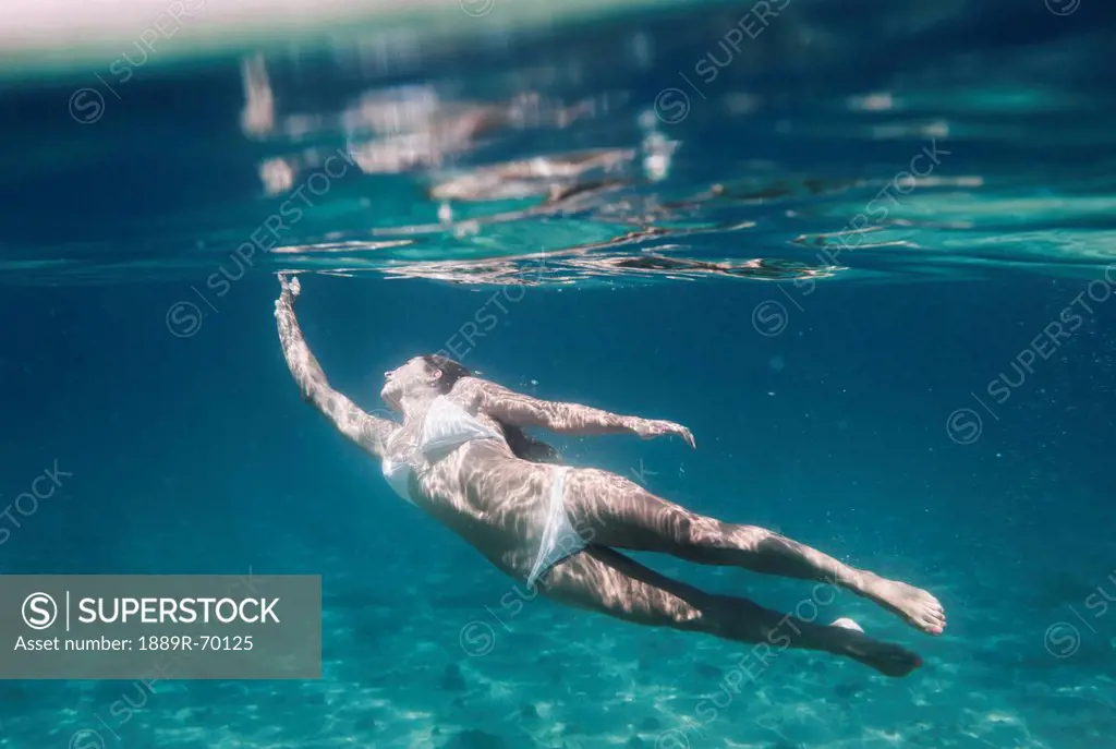 a woman swimming underwater wearing a two piece bathing suit, tarifa cadiz andalusia spain