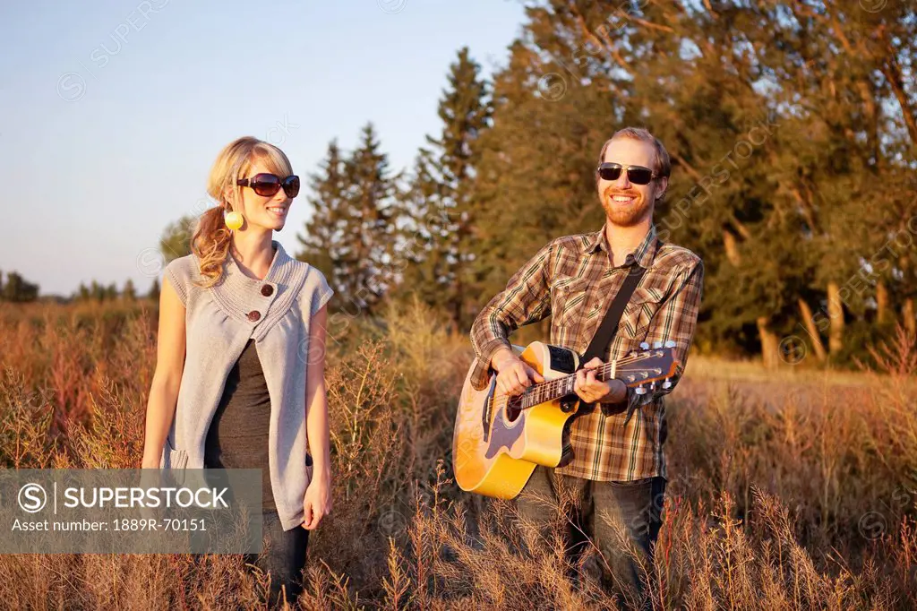 a couple standing in a field with a guitar, edmonton alberta canada