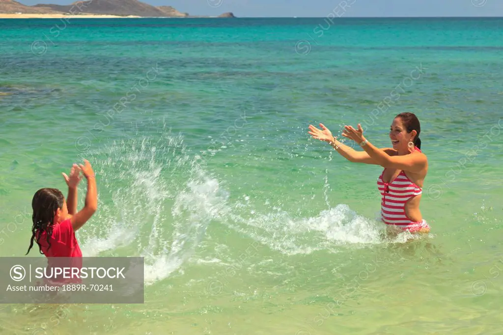 a mother and daughter playing in the water together at cabo pulmo, baja california sur mexico