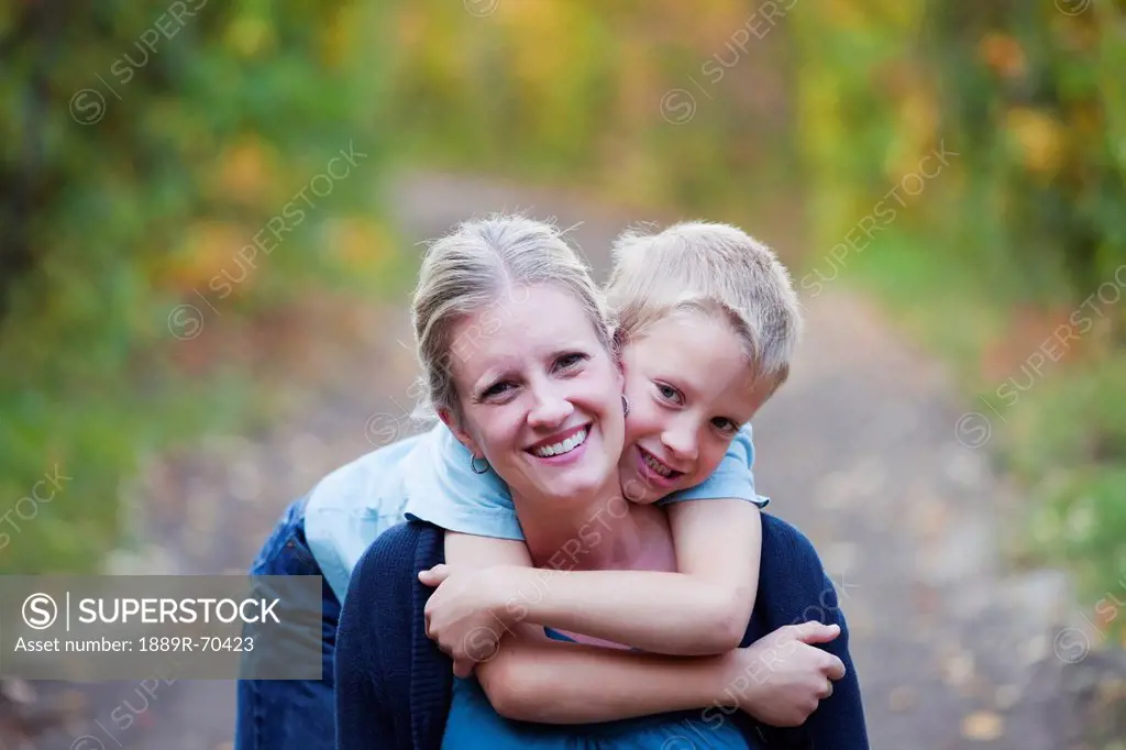 young boy embracing his mother on a park path in autumn, edmonton alberta canada