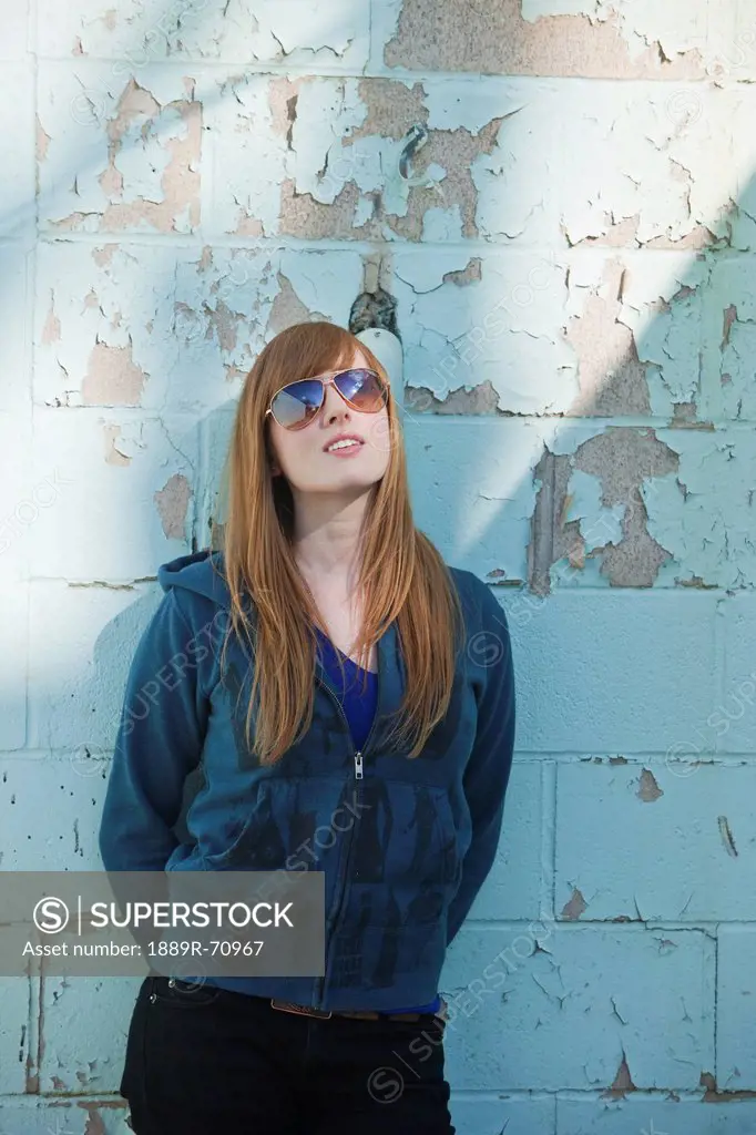 a young woman wearing sunglasses leaning against a wall, edmonton alberta canada