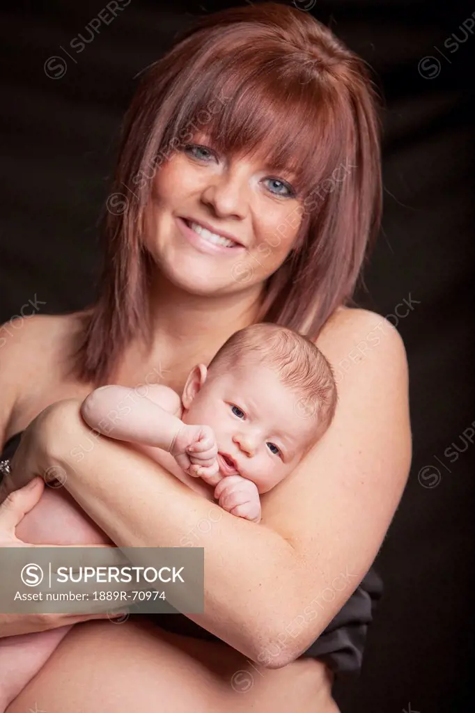 a mother holds her newborn baby with bare skin touching, edmonton alberta canada