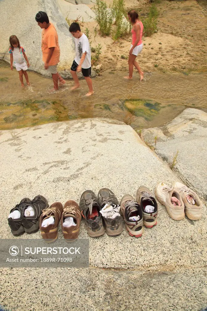 a family leaves their shoes on the shore and walks in the shallow water at the sierra la laguna biosphere reserve, baja california sur mexico