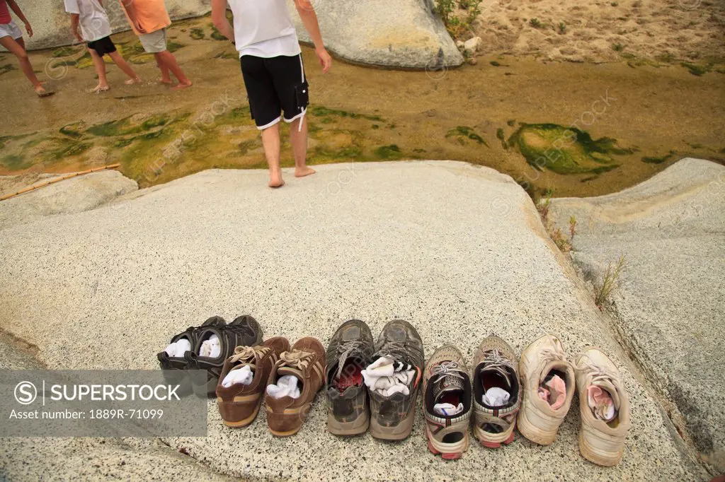 a family leaves their shoes on the shore and walks in the shallow water at the sierra la laguna biosphere reserve, baja california sur mexico